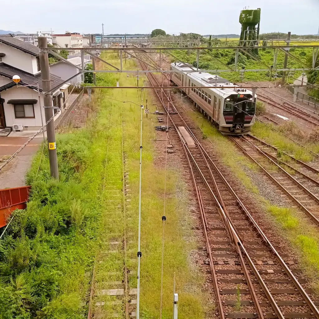 坂町駅周辺から新発田方面。左がJR米坂線。右がJR羽越本線、下り列車の普通列車が走っている。
