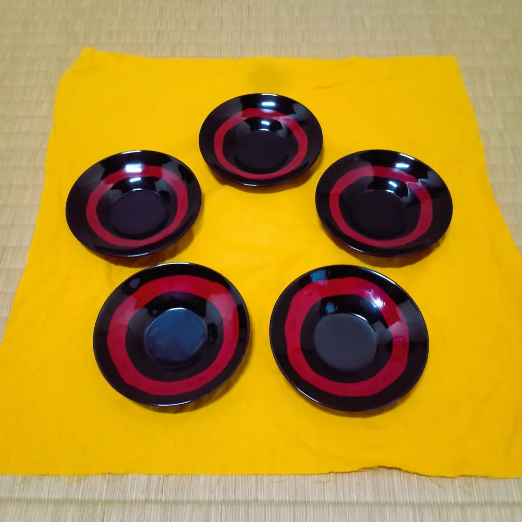 村上の漆器、乾漆の研ぎ出し茶托５枚、黄色い布の上に星形に並べてある。