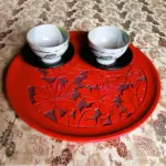 村上木彫堆朱、牡丹柄の丸盆に織部焼の湯飲み茶碗を二客載せて運ぶところ。