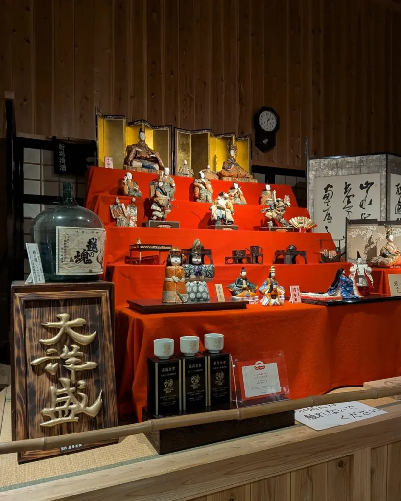 金屏風を背にした内裏雛や五人囃子、黒漆の道具類。