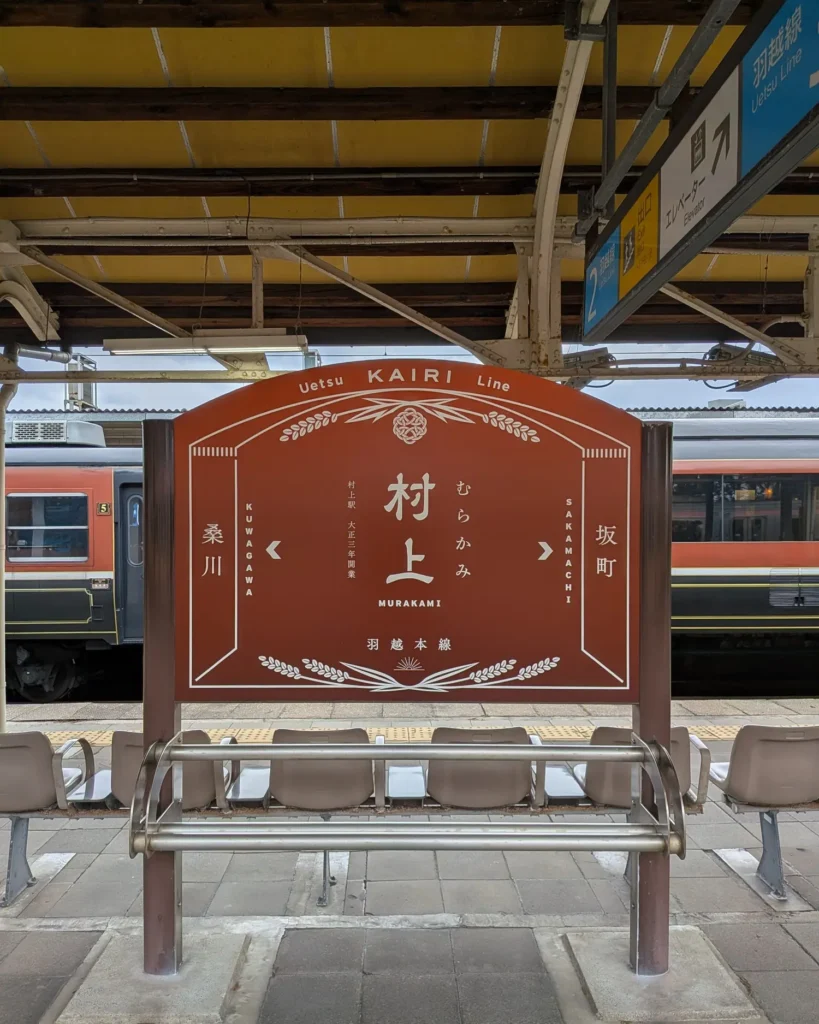 村上駅の駅名標。後ろに見えている車体がSL村上ひな街道号の客車です。