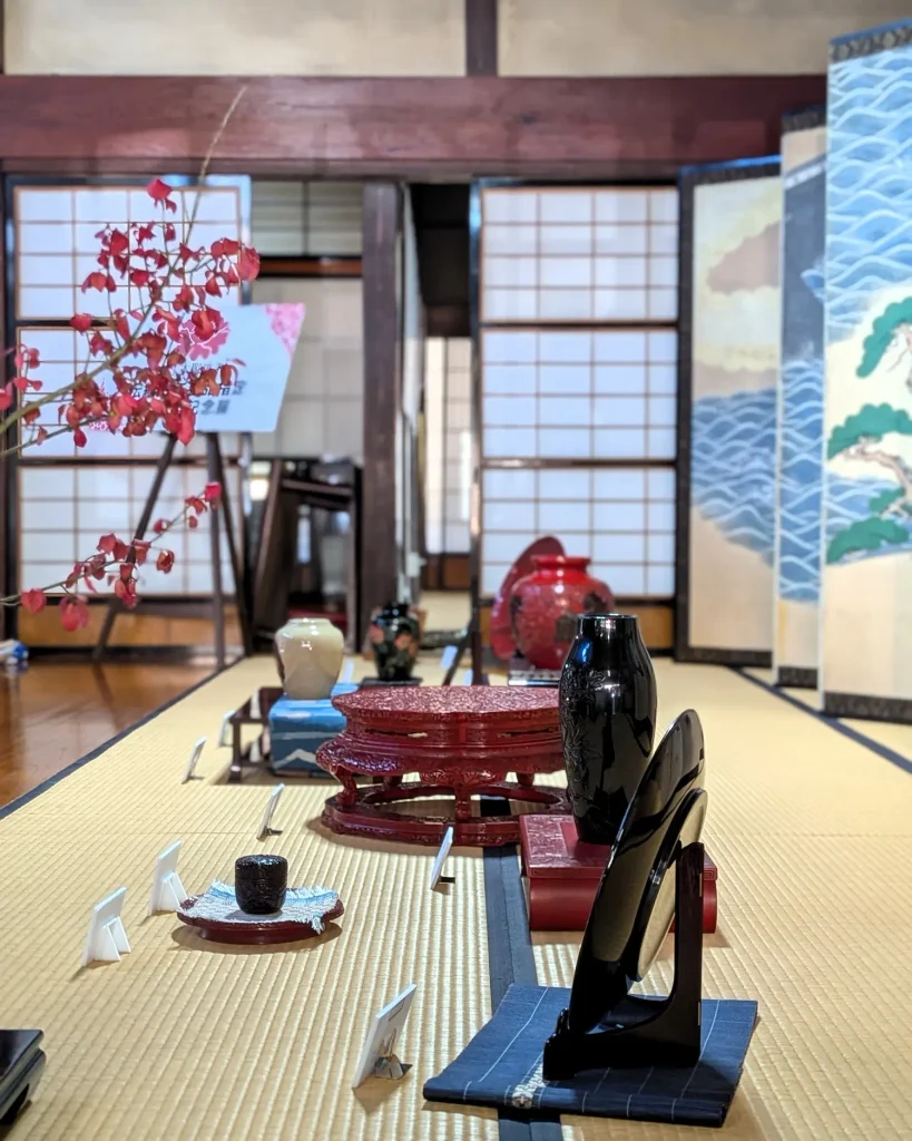 屏風を背景に並ぶ村上木彫堆朱 伝統的工芸品指定50周年記念展の作品