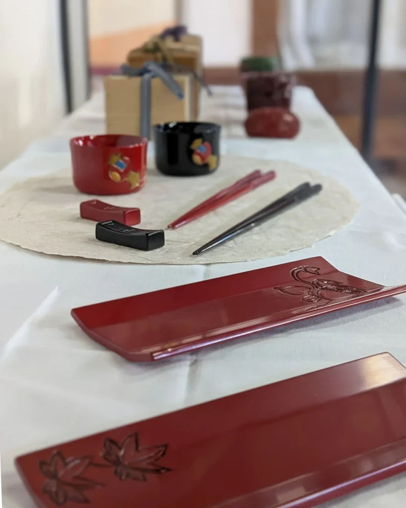 村上木彫堆朱 伝統的工芸品指定50周年記念展に並ぶ箸や猪口、おしぼり置きなどの作品