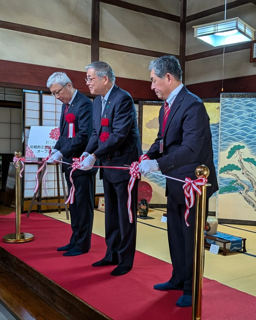 村上木彫堆朱 伝統的工芸品指定50周年記念展のオープニングセレモニーで、テープカットを前に並ぶ関係者