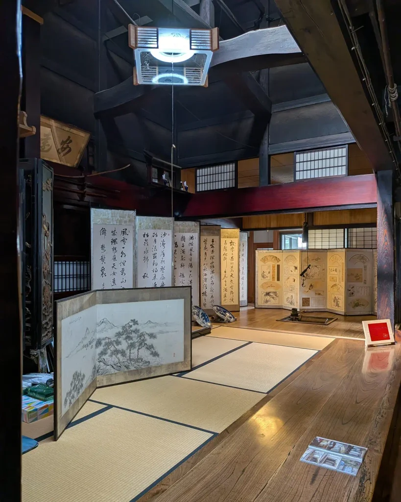 吉川酒舗の高い吹き抜けの町屋内部に並ぶ書画や扇面の屏風