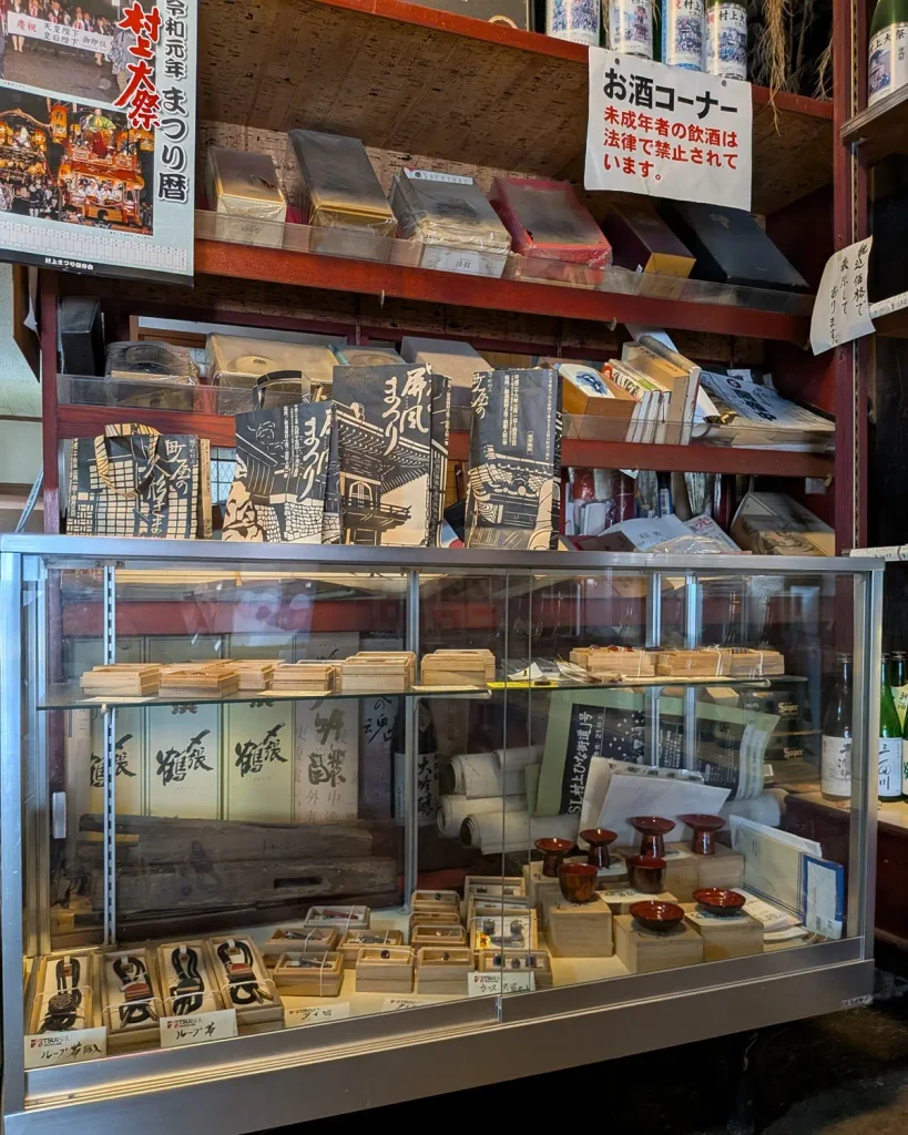 吉川酒舗の店内に並ぶ地酒や小物、町屋の屏風まつりの案内冊子