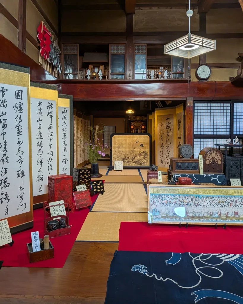 益田甚兵衛酒店の座敷に並ぶ書の屏風や村上堆朱、昔のラジオなどの展示