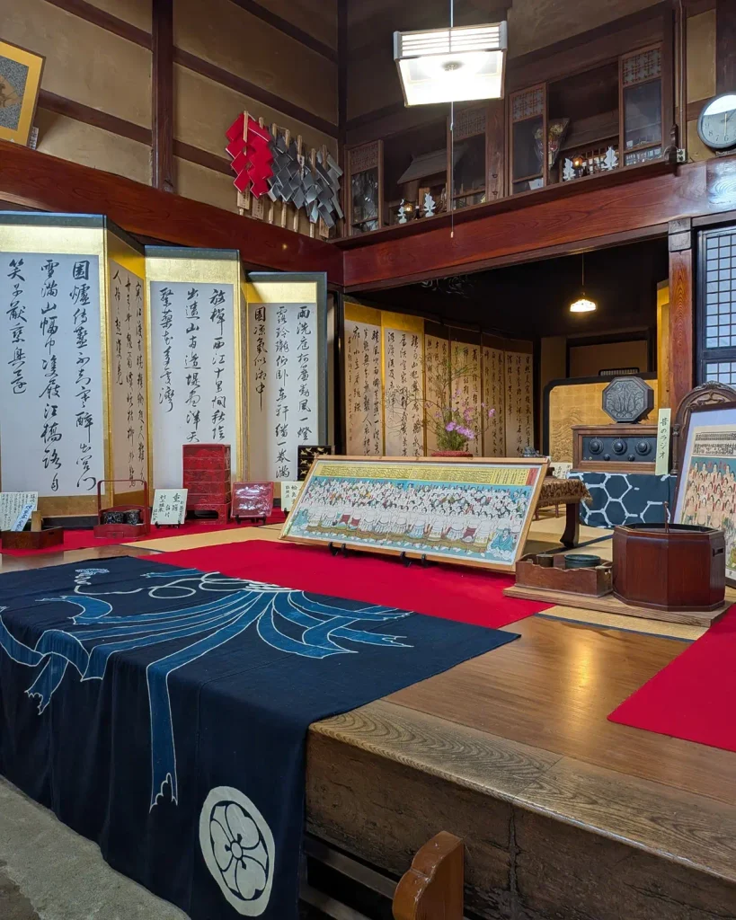 益田甚兵衛酒店の町屋の座敷に並ぶ書の屏風と昔の道具
