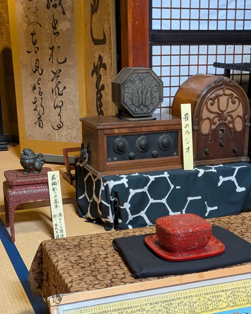 益田甚兵衛酒店に展示された屈輪彫りの高卓と木製の昔のラジオ