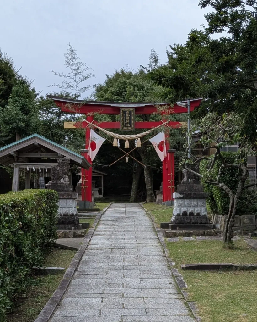 瀬波大祭本祭りの日の西奈彌神社。赤い鳥居にしめ縄と日の丸が掲げられている