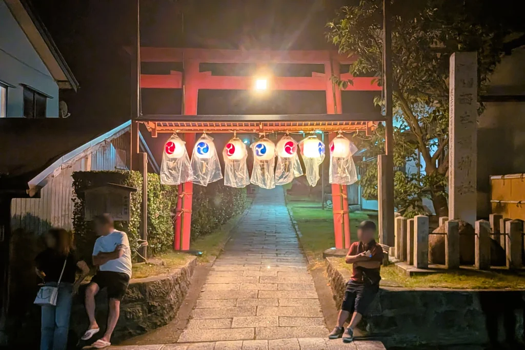 瀬波大祭の夜、提灯が灯された西奈彌神社の鳥居と参道