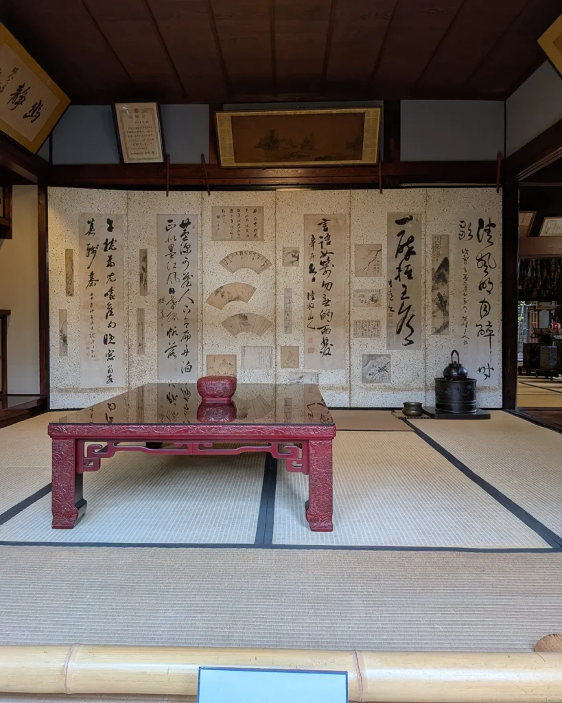 千年鮭きっかわの座敷に展示された書画を貼り交ぜた屏風と朱塗りの卓